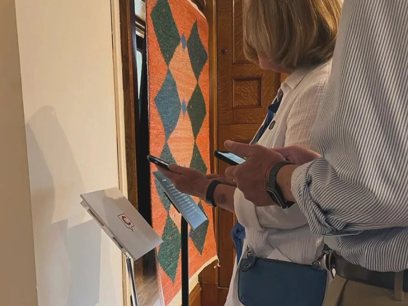 Visitors use smartphones beside a Capption indicator in the Turnblad Mansion