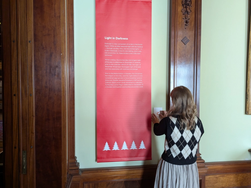 A visitor taps a Capption indicator beside the Light in Darkness exhibit panel