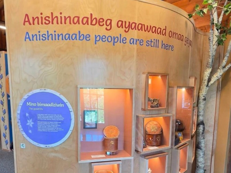 Anishinaabeg exhibit displays with bilingual text and a Capption indicator