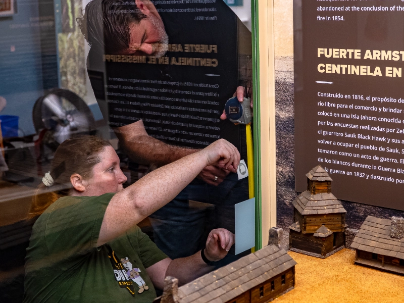 Putnam staff install a Capption marker beside a bilingual exhibit display