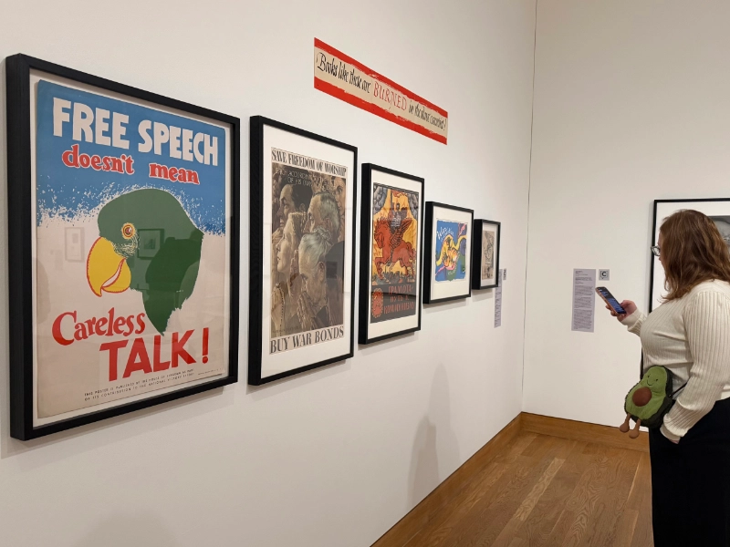 A visitor uses Capption beside a gallery display of wartime posters