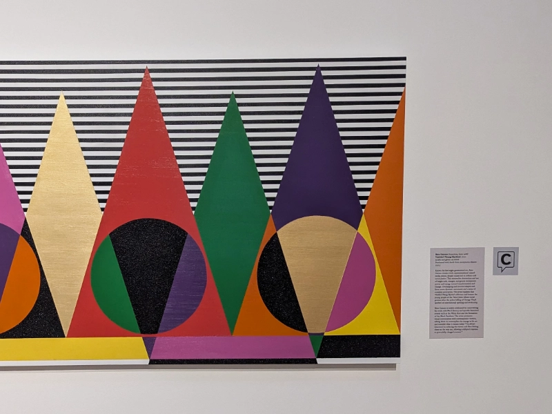 A Capption indicator beside a colorful geometric artwork