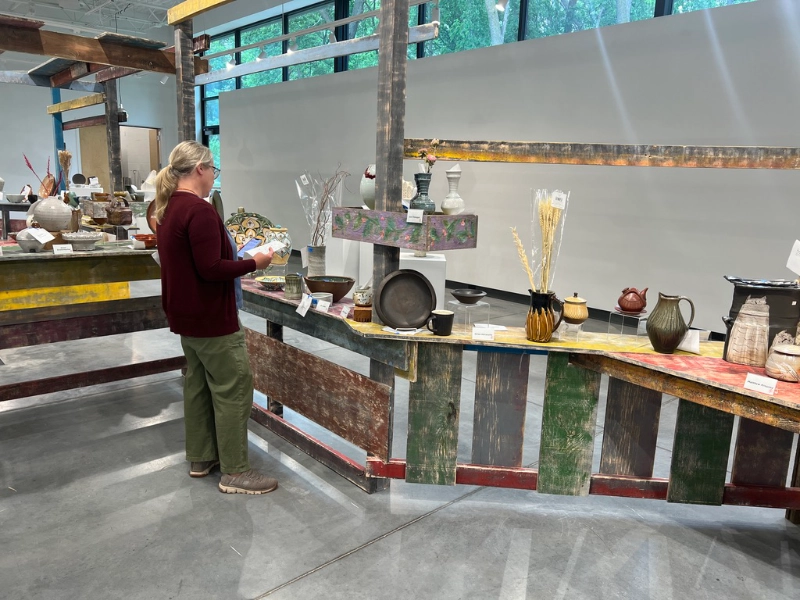 A visitor uses a smartphone while viewing pottery in the Ford Family Gallery