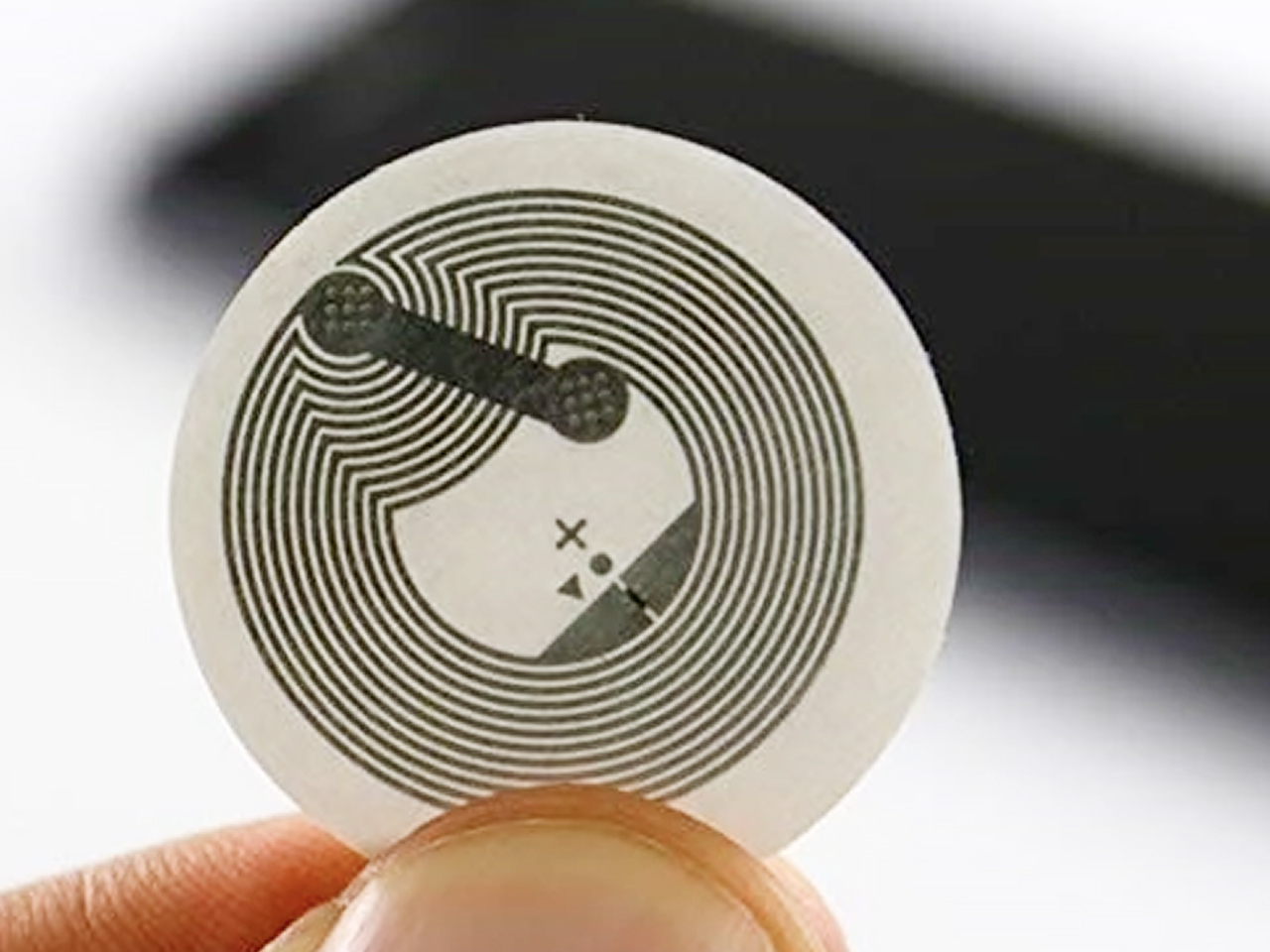 Close-up of an NFC sticker tag held between two fingers